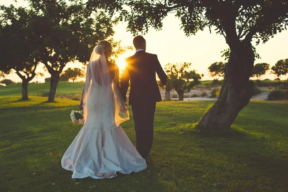 Bride and groom walking hand in hand at sunset