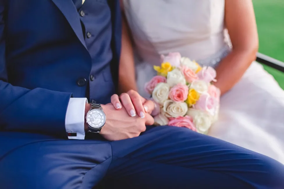 Bride and groom hold hands with bouquet