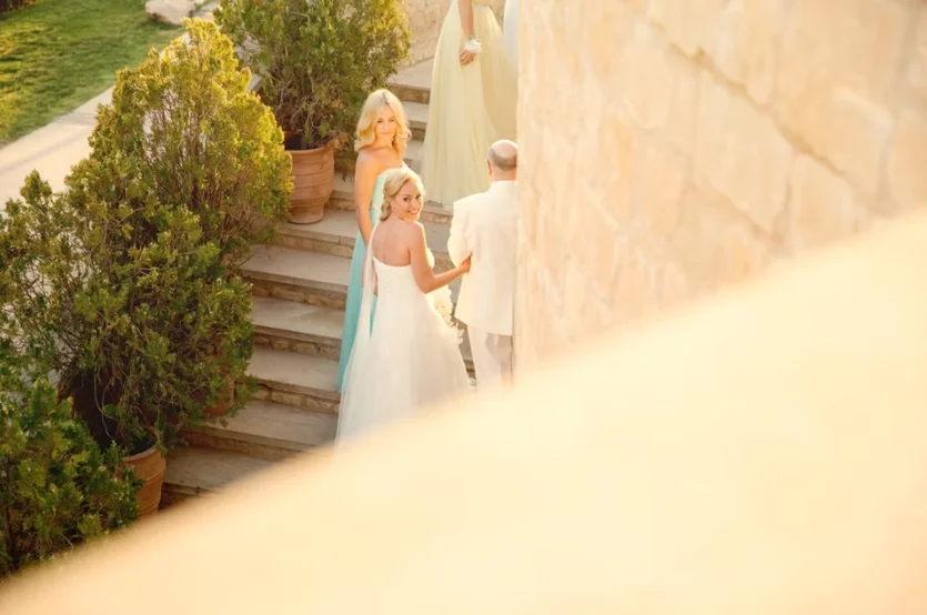 Bride looking back at the camera holding the grooms arm walking up stairs