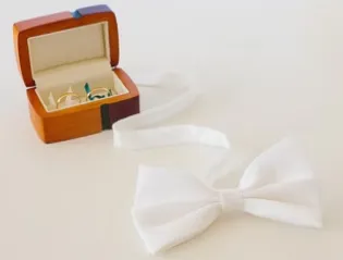 Two gold wedding rings in a box and white bow tie