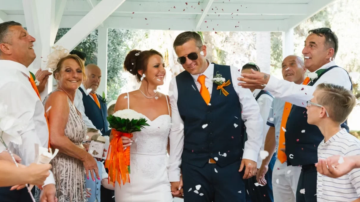 Bride and groom sprinkled with confetti down the aisle