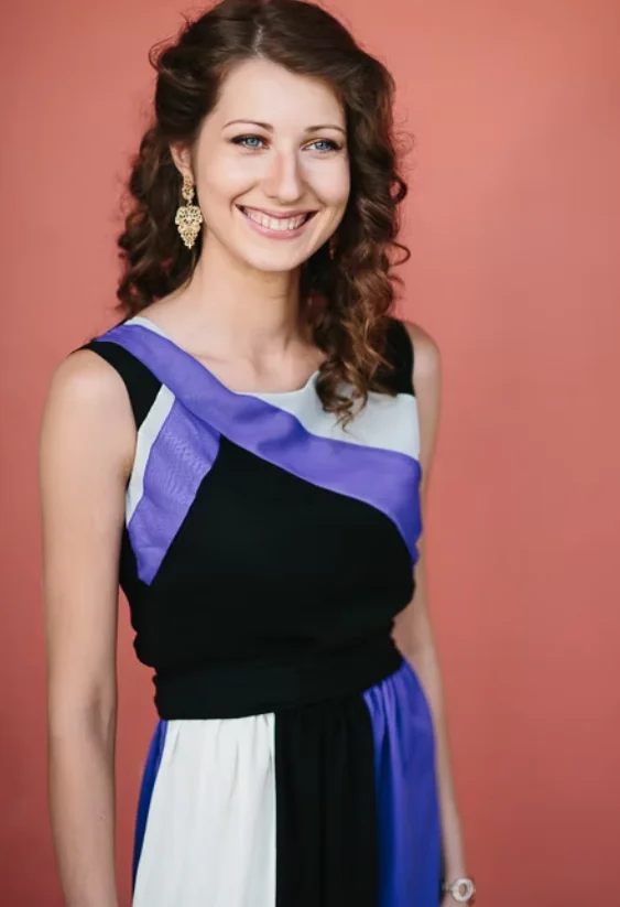Female model smiling, wearing a black, purple and white dress