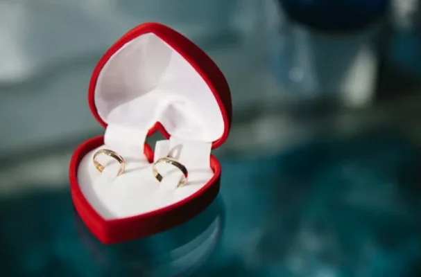 Two gold wedding rings in a red heart shaped box