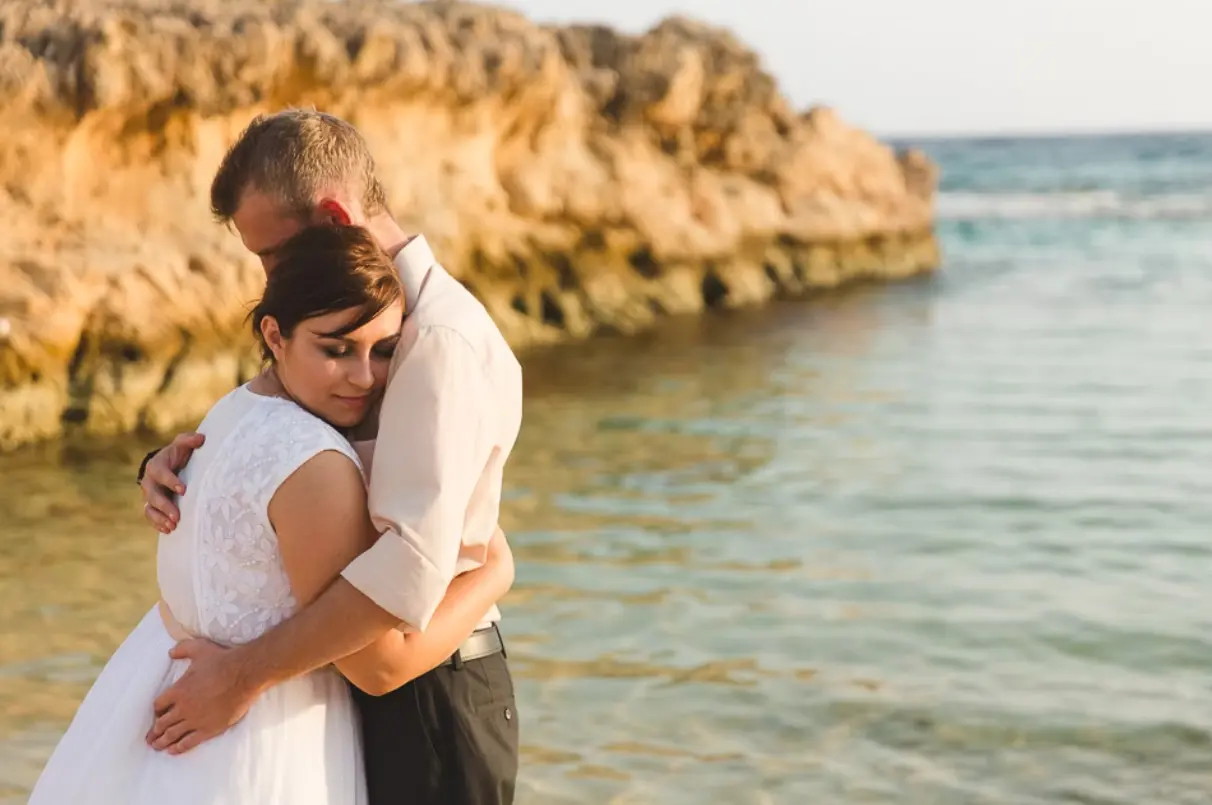 Embracing couple with the sea behind them