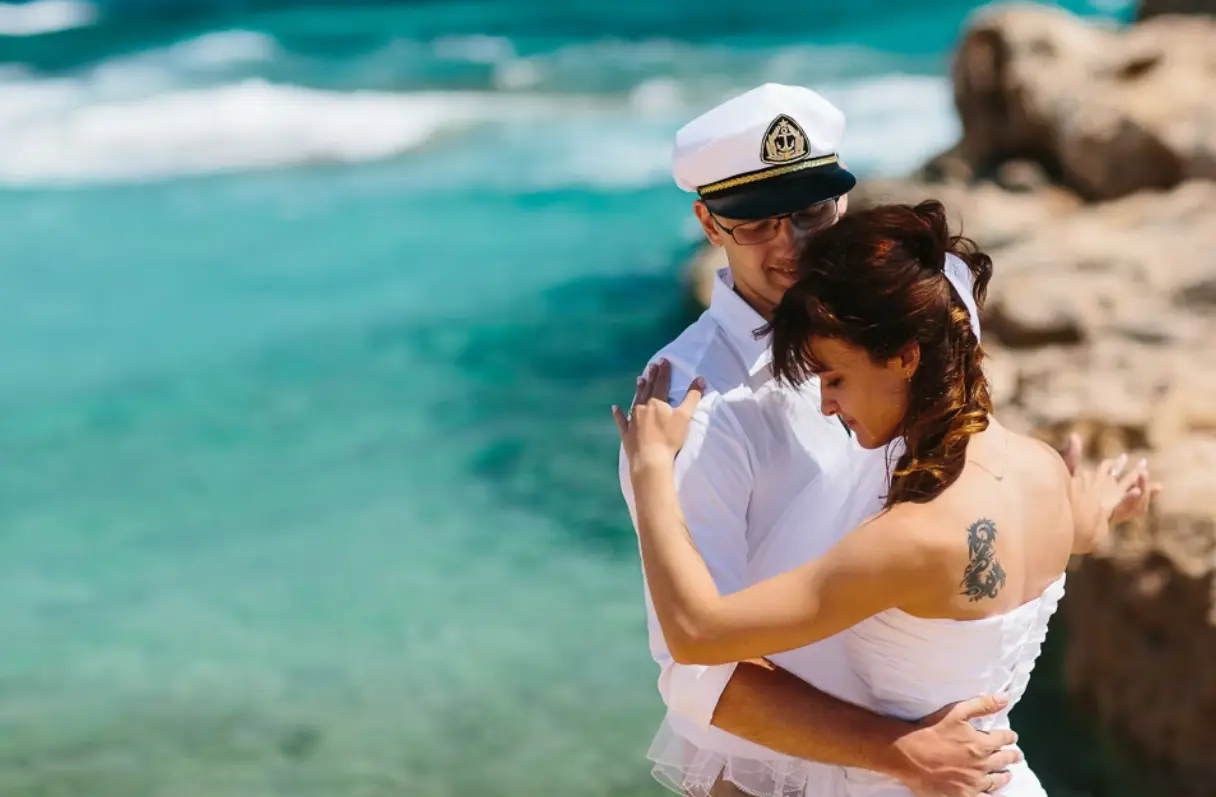 Embracing couple with the sea behind them