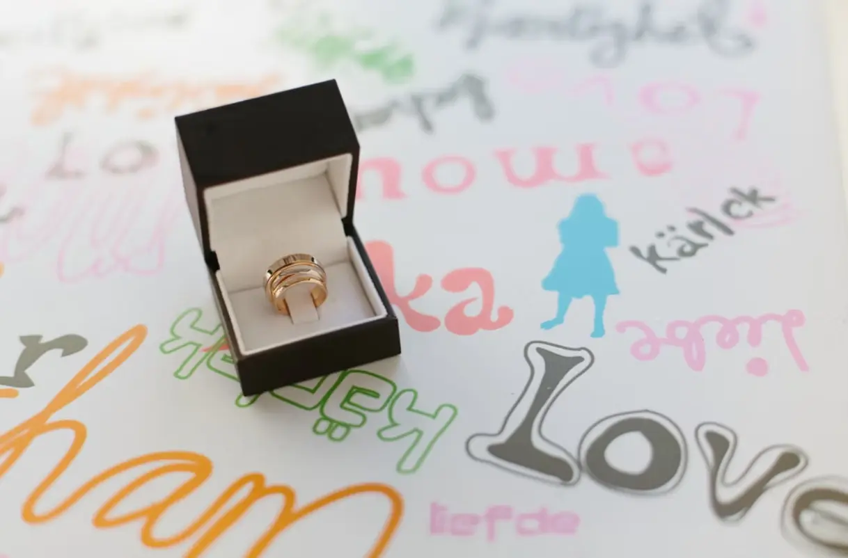 Two wedding rings in a box with writing on the surface below including the word love