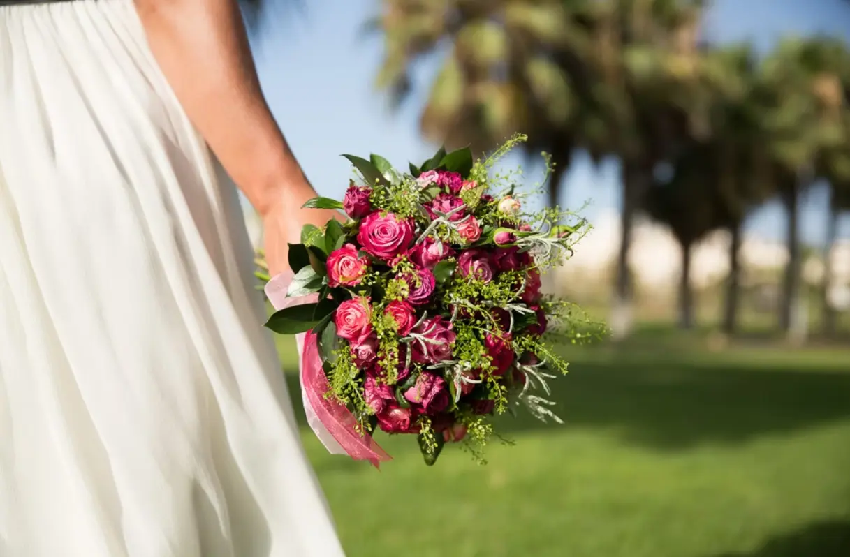 Bride holding a bouquet of pink roses and greenery