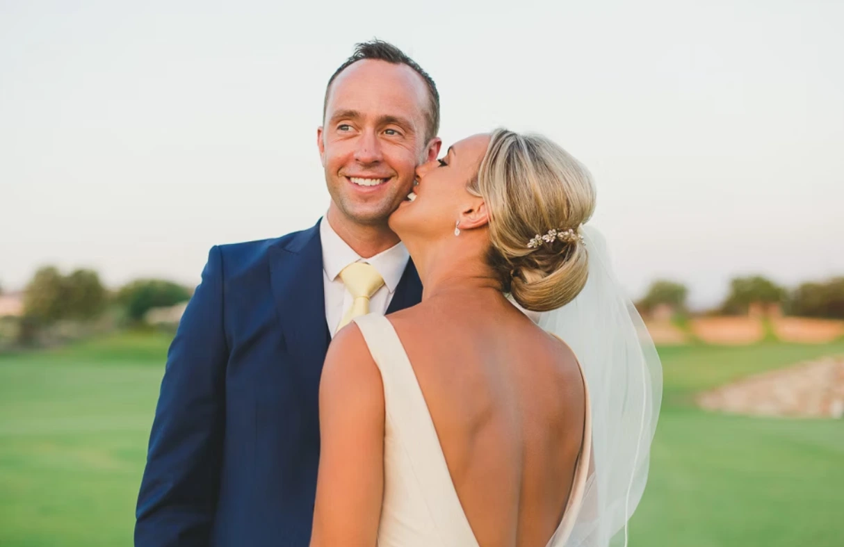Bride kissing smiling groom on the cheek