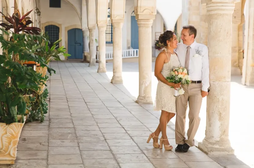 Man and woman standing together beneath stone arches during relaxed wedding photoshoot