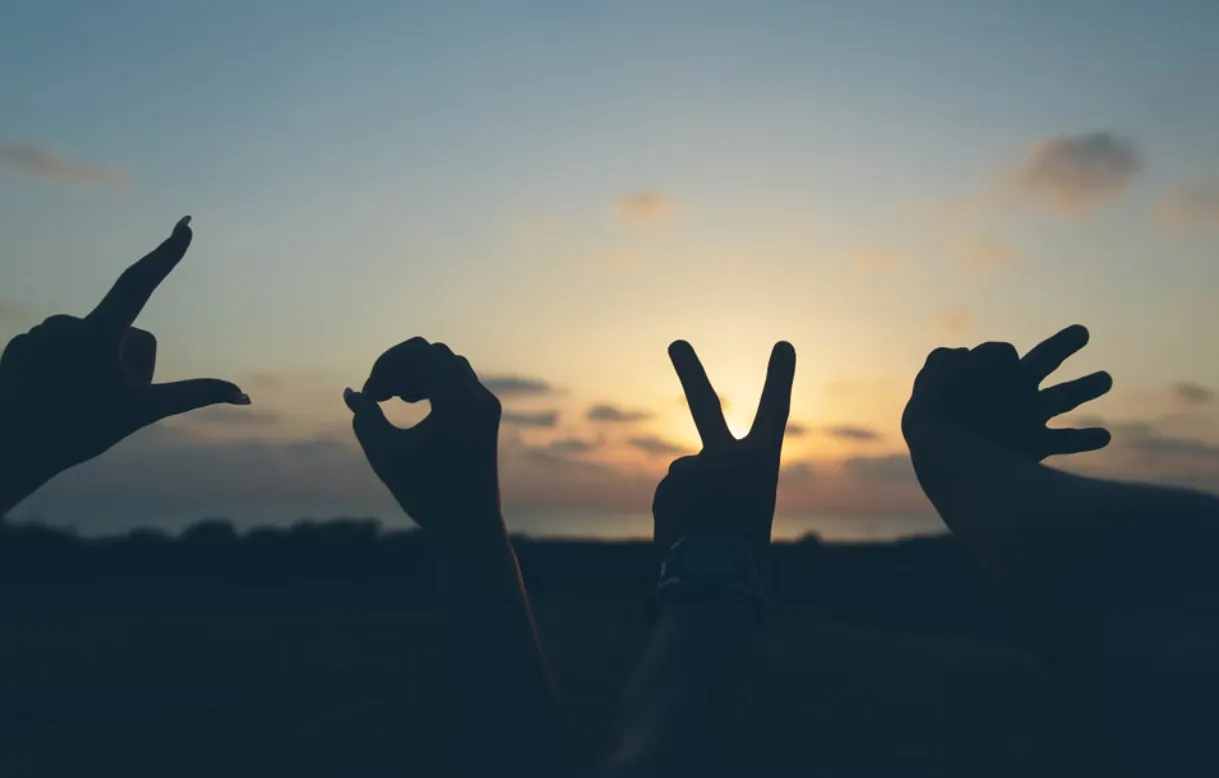 Hands spelling out the word love, silhoutted at sunset