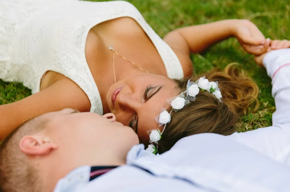 Bride and groom laid on the grass looking at each other