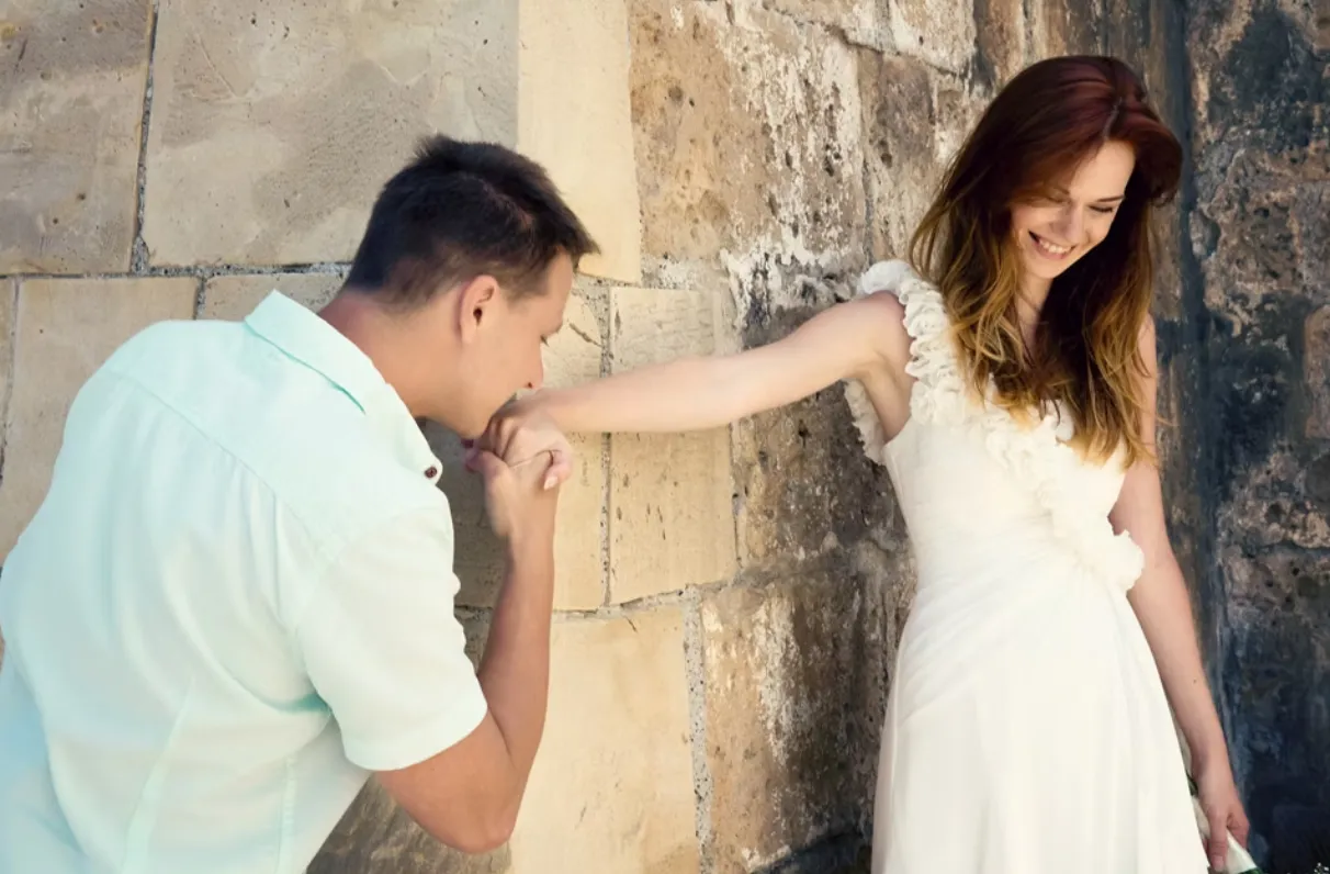 Groom kissing smiling brides hand
