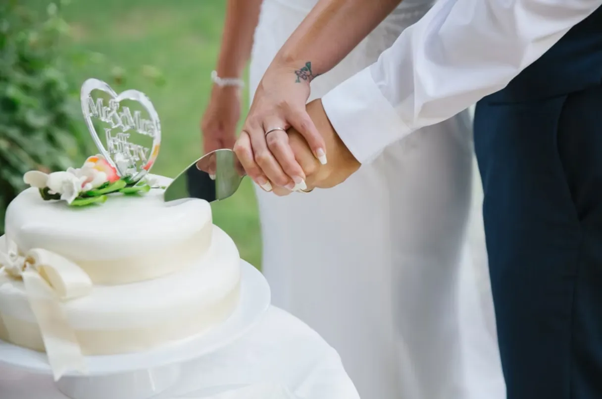 Close up shot of the wedding cake being cut by the bride and groom with a knife