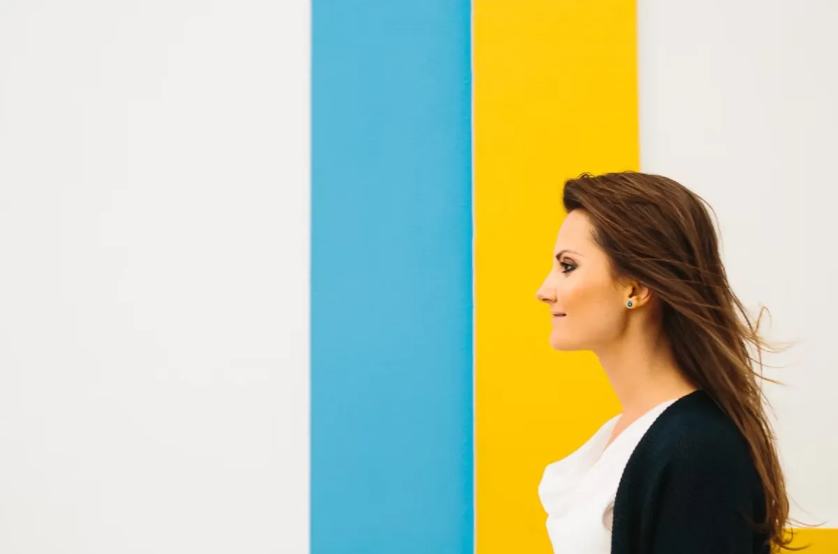 Profile portrait of Katrin Allison standing against bold colourful wall